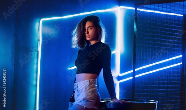 Obraz Beautiful girl in the studio with neon bright blue lights in shorts