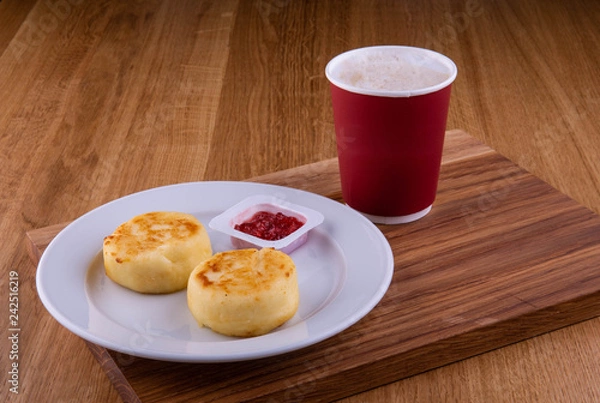 Fototapeta Cherry jam with cheesecakes on a plate, is served with a cup of coffee