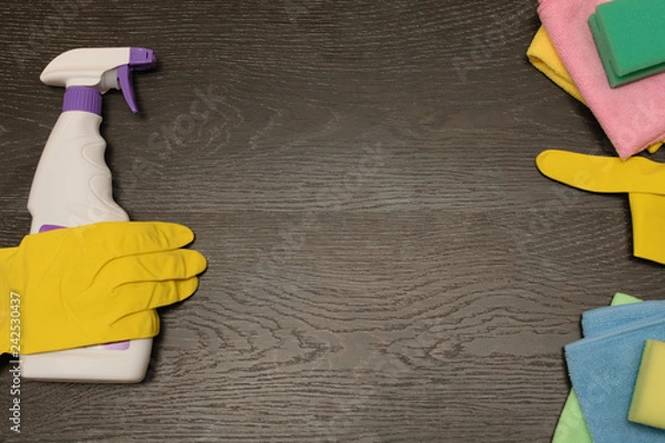 Fototapeta goods for cleaning the house, cleaning liquid with rubber gloves rags and sponges on wooden background, copy space.