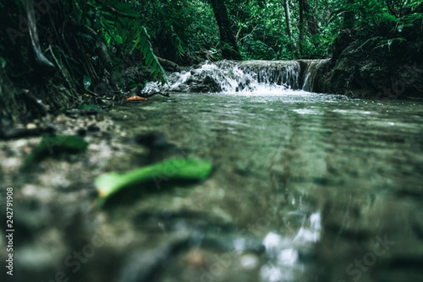 Fototapeta view of a beautiful waterfall in Thailand in a green jungle and clean environment in a moody green tone look surrounded with big trees and clear fresh green water which suggests an eco environment