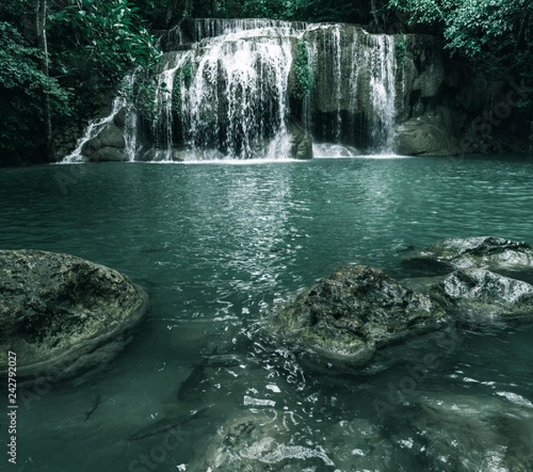 Fototapeta view of a beautiful waterfall in Thailand in a green jungle and clean environment in a moody green tone look surrounded with big trees and clear fresh green water which suggests an eco environment