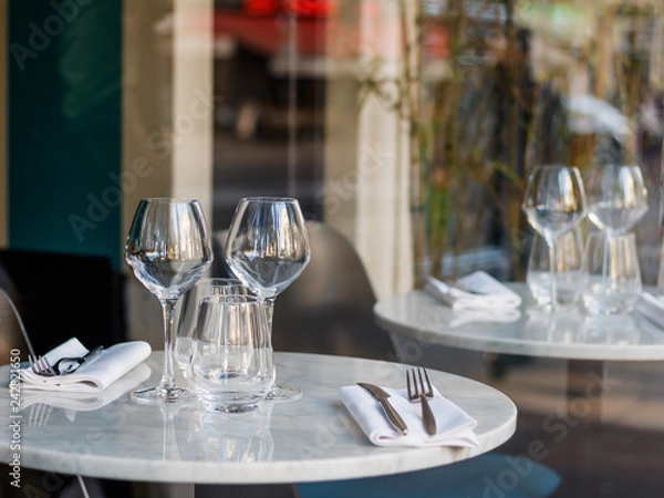 Fototapeta Table setting in a French restaurant for two. View through a window from a street.