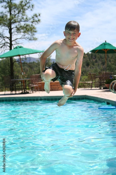Obraz young boy smiling and jumping into a swimming pool