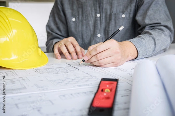 Fototapeta Construction engineering or architect hands working on blueprint inspection in workplace, while checking information drawing and sketching for architecture project working