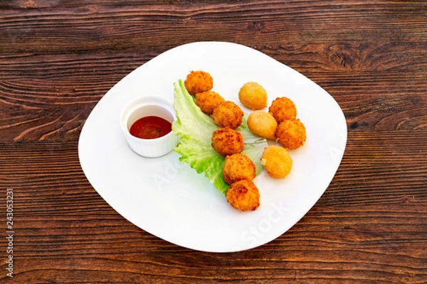 Obraz Cheese balls on a white plate with lettuce leaves and sauce