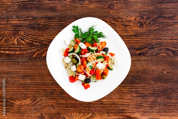 Obraz Greek salad of fresh cucumber, tomato, sweet pepper, lettuce, red onion, feta cheese and olives with olive oil. Healthy food, top view