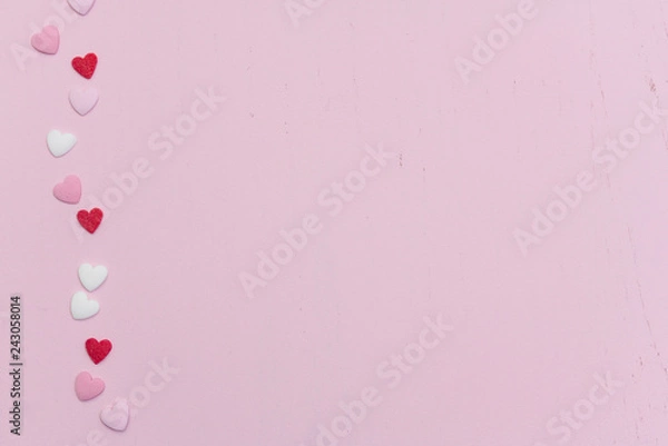 Fototapeta Flat lay with hundreds of tiny heart-shaped sugar sprinkles with space for copy text or love letter message as gift of symbol for affection and romantic feelings for Valentine's Day on February 14th