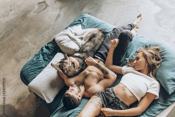 Obraz Beautiful loving couple in bed together with the dog