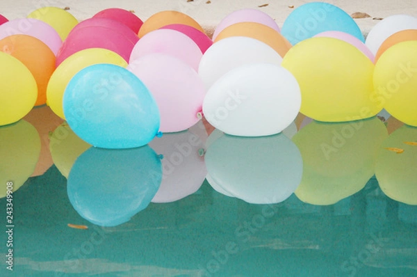 Fototapeta Lots of colorful balloons floating on the water with reflections.