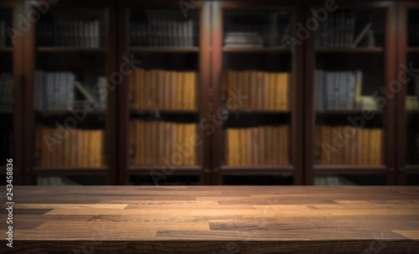 Fototapeta Blured bookshelf in small home library in the background. Table top for product display montage. Dark interior design.