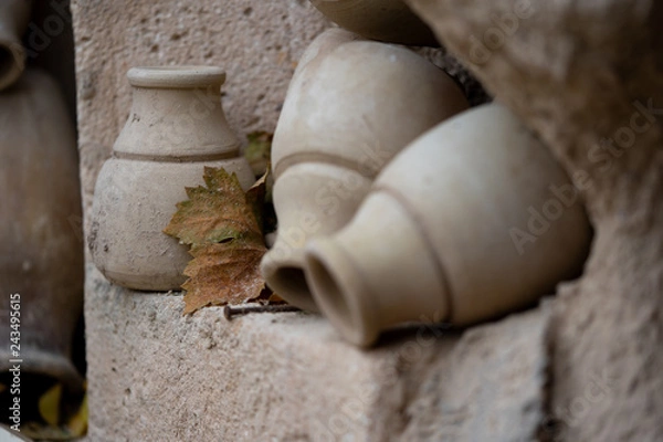 Obraz Antique ancient stone utensils vase on stone wall and grape leaf
