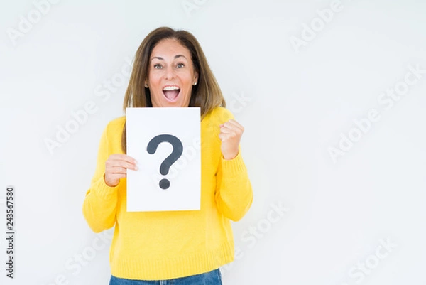 Fototapeta Middle age woman thinking and holding paper with question mark symbol over isolated background screaming proud and celebrating victory and success very excited, cheering emotion
