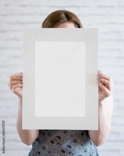Obraz Woman holding a blank poster on wall background