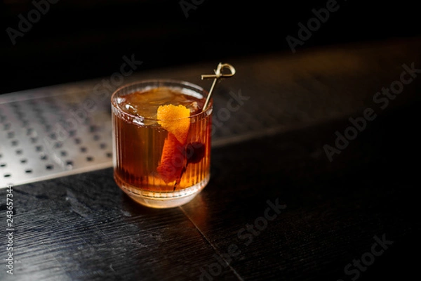 Fototapeta Glass of a Old Fashioned cocktail on the wooden steel bar counter