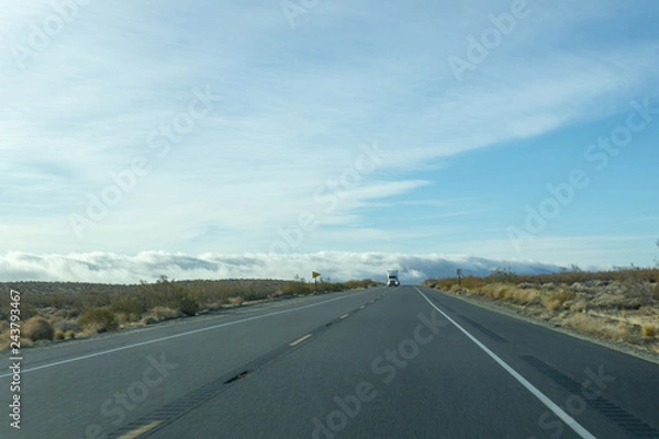 Fototapeta Semi emerges from the fog on a two lane freeway
