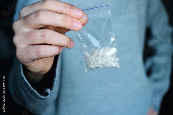Fototapeta hand holds packet with white narcotic - cocaine, meth or another drug