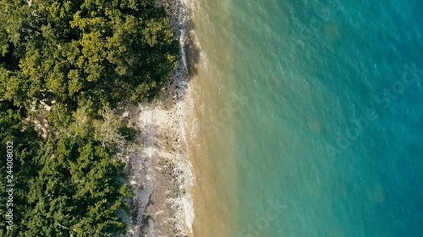 Obraz stunning aerial drone minimal geometric image of a remote tropical sea ocean shore with sandy rocky beach lush rainforest jungle and crystal clear azure blue water from top looking down