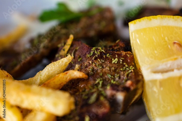 Fototapeta Delicious Serving Of Grilled Large T-Bone Steak Seasoned With Herbs By French Fries And Lemon Slice