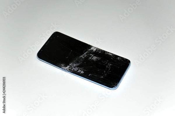 Fototapeta Broken smartphone on a white background. The screen of the phone is broken and scratched.