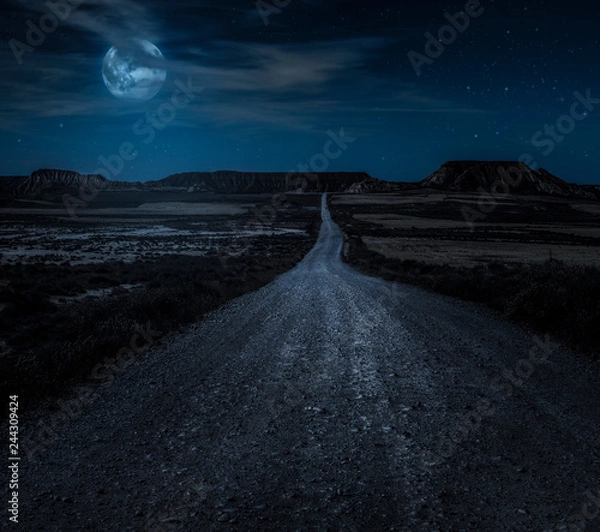 Obraz Moon, stars and clouds in the night. Wild west road illuminated from the moon. Moonlight and road background.