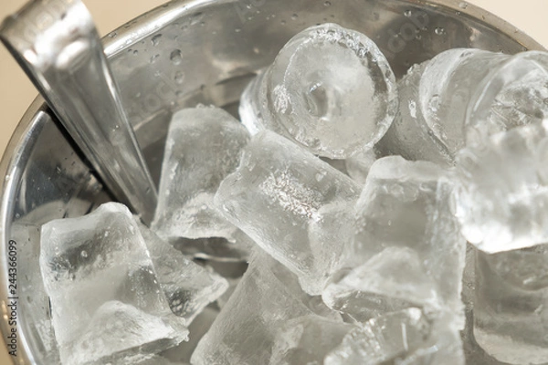 Fototapeta A silver bucket made from aluminum full filled with ice cube is placed on the table at the pub, ice were made for make water, whisky, vodka or alcohol drinking cold