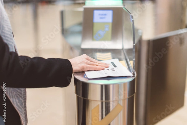 Obraz Electronic Boarding pass and passport control in the airport - hand with boarding pass at the turnstile.