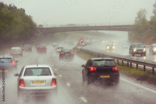 Obraz Traffics on a rainy wet highway in fog water spray