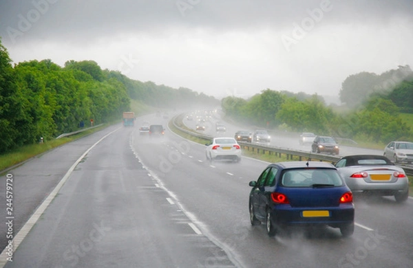 Obraz Traffics on a rainy wet highway in fog water spray