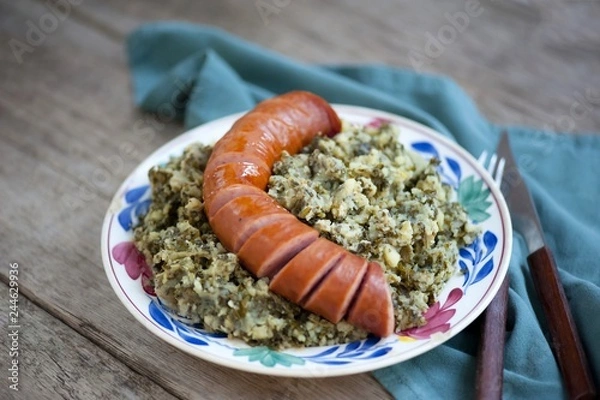 Fototapeta Rustic cuisine with “Boerenkool spamppot” or smoked sausage cabbage, traditional Dutch food. With a typical Dutch plate. stamppot boerenkool .