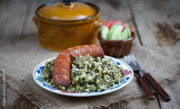 Fototapeta Rustic cuisine with “Boerenkool spamppot” or smoked sausage cabbage, traditional Dutch food. With a typical Dutch plate. stamppot boerenkool .