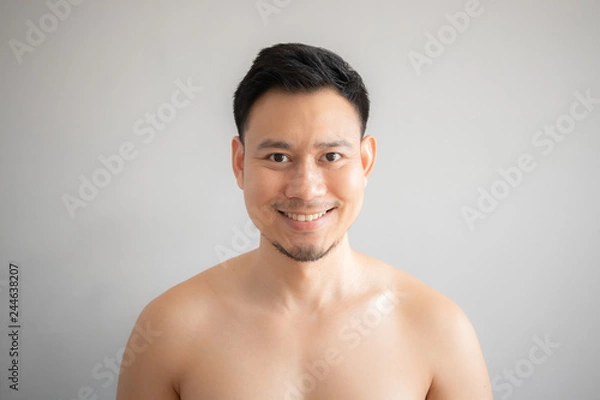 Fototapeta Smile Asian man in topless portrait isolated on gray background.