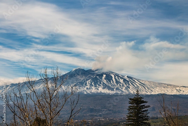 Fototapeta A beautiful view of the eruption of volcano Etna with smoke and snow is in the photo in winter in Sicily