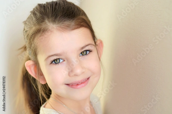 Obraz portrait of a little caucasian white beautiful brunette girl with pony tail on neutral background. smiling toothless green eyed happy girl with cute protruding ears. Kid expression portrait with fun h