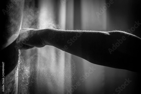 Fototapeta Shadowy, Black & White Close Up Action Photo of a Bare Knuckle Fist Hitting a Punching Bag with an Explosion of Dust
