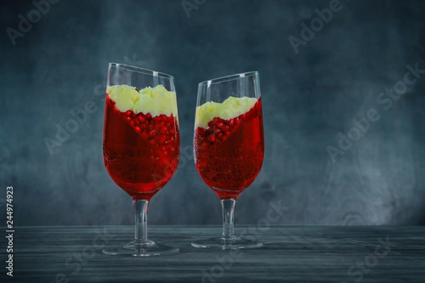 Fototapeta Panna cotta dessert with pomegranate seeds jelly on rustic wooden background. Holiday food concept.