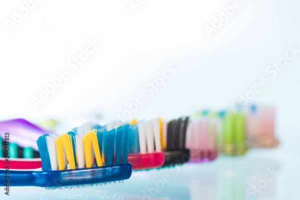 Fototapeta Several toothbrushes one by one next to the toothpaste