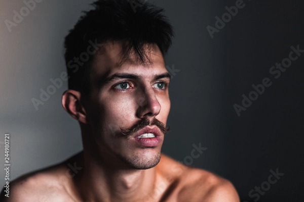 Fototapeta Młody przystojny mężczyzna z wąsem myśli przy oknie