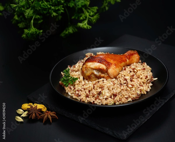 Fototapeta grilled chicken leg with wild rice on a black background