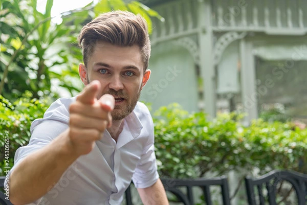 Obraz Young furious caucasian businessman shouting and pointing camera . Angry man and cursing .Anger, emotions, aggression,  Negative human emotions concept