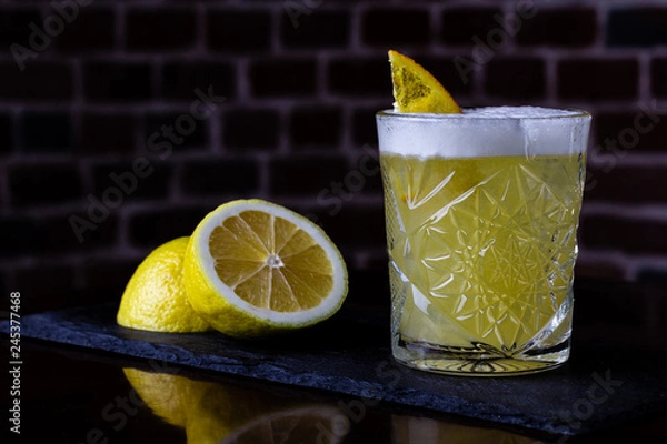 Fototapeta A classic recipe for whiskey sour - with bourbon, cane syrup and lemon juice, garnished with orange. Traditional aperitif. Space for text