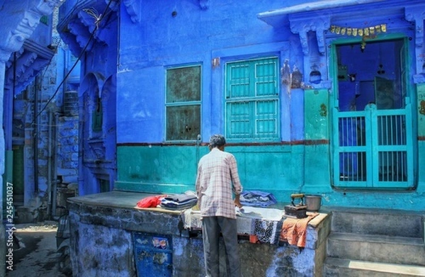 Fototapeta Mężczyzna prasujący ubrania starym żelazkiem na środku ulicy Jodhpur, czyli „błękitnego miasta” w Indiach, w stanie Radżastan