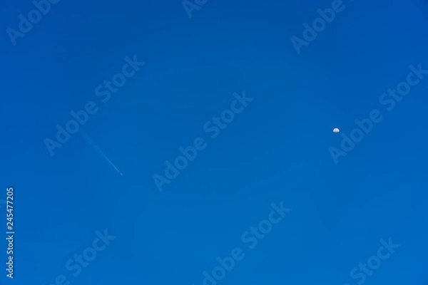 Obraz An airplane flying in the sky and half moon appear.
