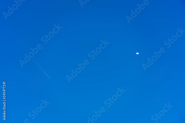 Obraz An airplane flying in the sky and half moon appear.