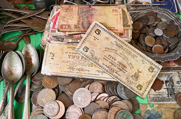 Fototapeta Very old Philippine bank notes and coins mixed with antique spoons on a table in a wet market in the city of Iloilo, Philippines