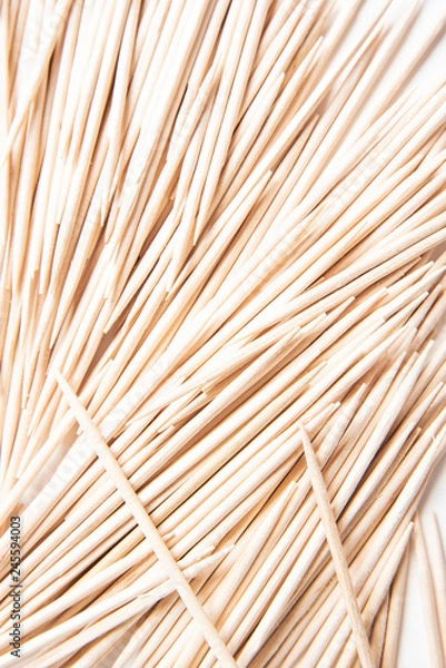 Obraz A bunch of unused round toothpicks from light-colored wood arrayed on a white plain background.