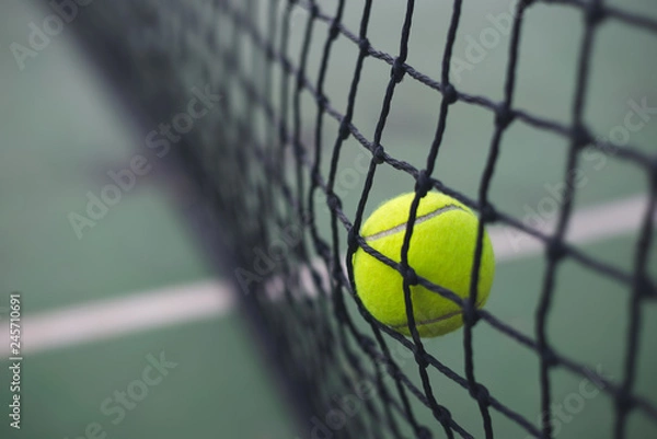 Fototapeta Close up tennis ball hitting to the net on court background with copy space
