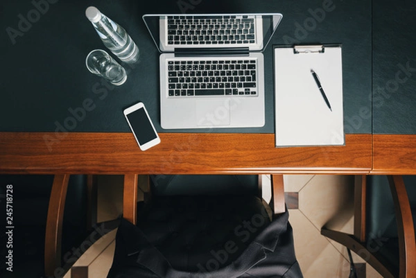Obraz Workplace in the office/ Workplace in the office of a businessman. View from above. Laptop, phone, jacket.