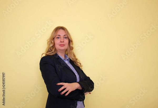 Obraz Business young blond woman in a blue shirt and jacket on a yellow background.  Copy space for text.
