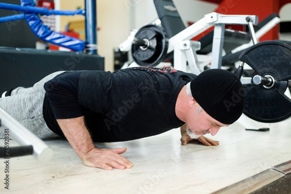 Obraz Adult man doing bench press in the gym