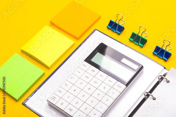 Fototapeta calculator on Notepad and stickers next isolated on yellow background